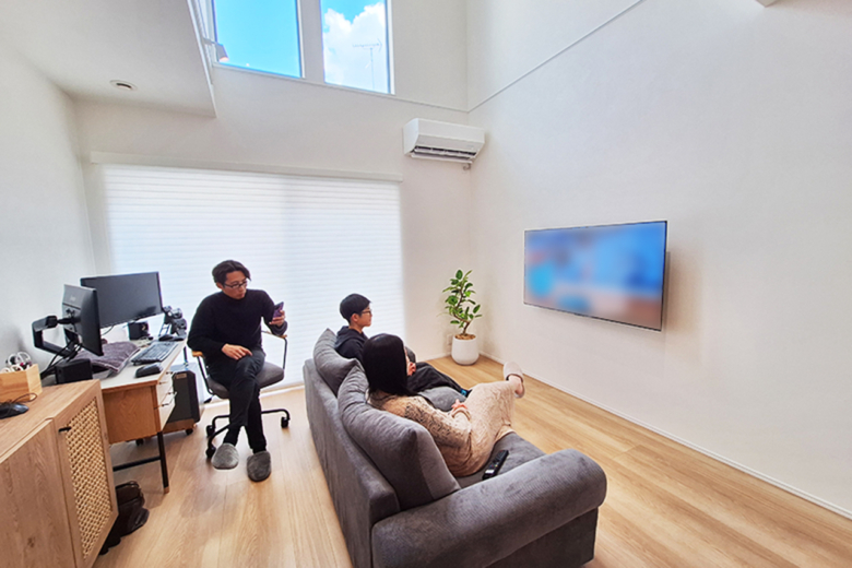 吹き抜けの大窓から自然光が差し込む、開放感あふれるリビング。壁掛けテレビとすっきりとした空間設計が、美しく整った暮らしを叶えています。
